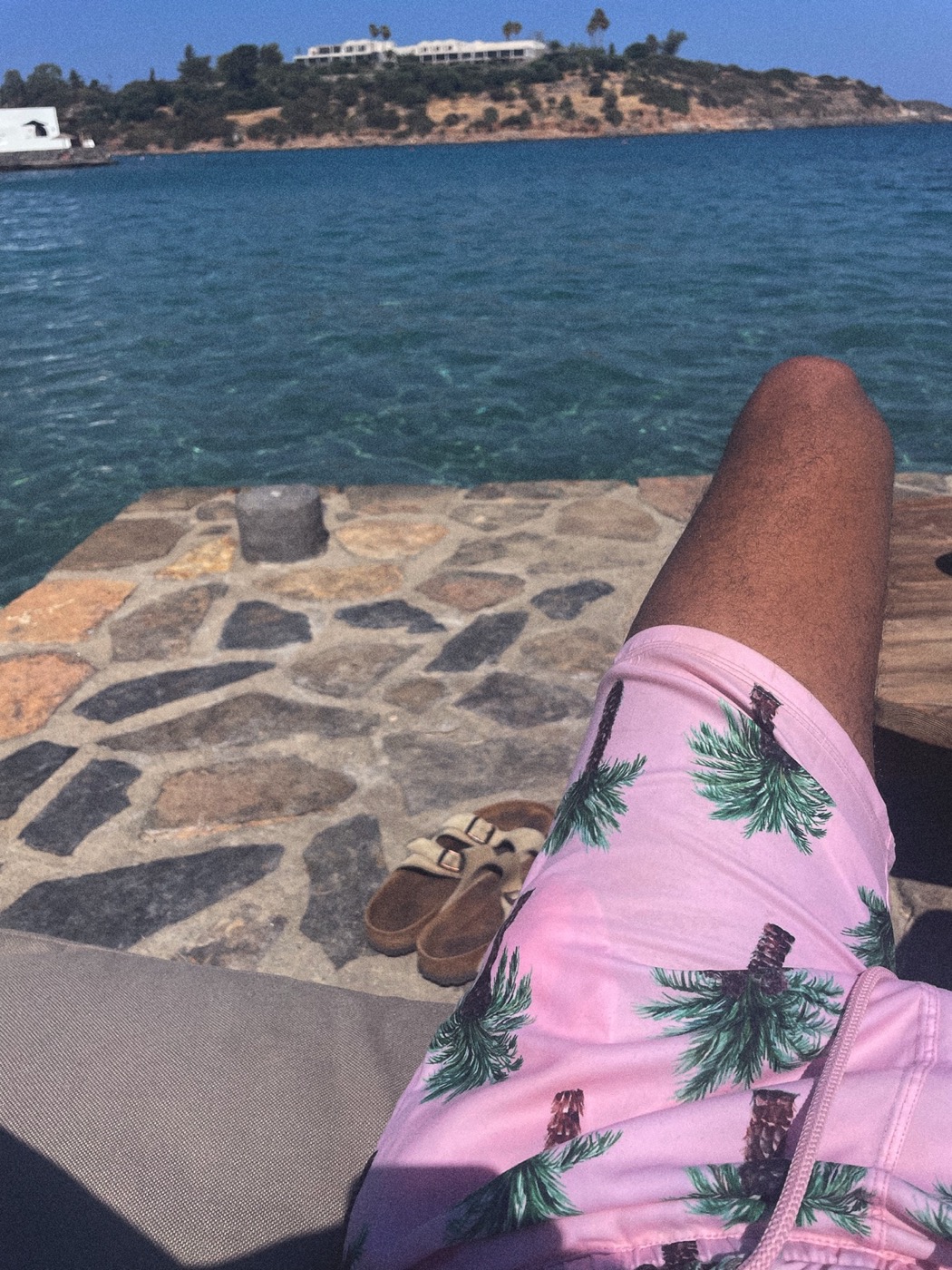 Murjan pink swim shorts on a stone pier